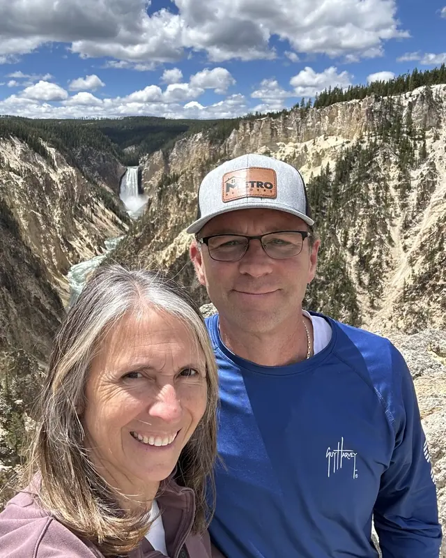 Teresa and Chris smiling at an overlook above a waterfall in Yellowstone